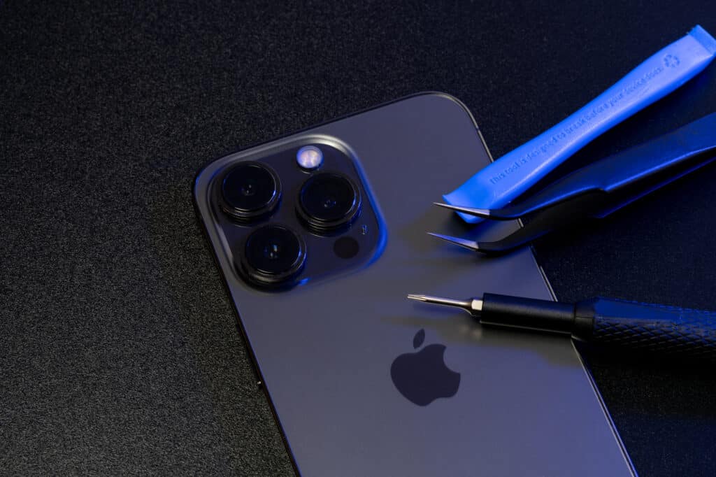 Repair tools on top of Apple iPhone Pro. Screwdriver and Tweezers